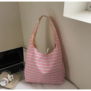 Detail of red and blue checkered canvas tote bag with drawstring and laptop on a desk