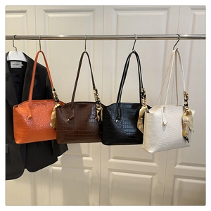 Dettaglio di quattro borse tote con motivo a coccodrillo e foulard decorativi colorati