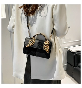 Detail of black matte leather handbag with leopard print scarf wrapped around the handle