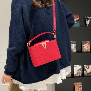 Sac à main rouge texturé litchi avec décor V doré et longue bandoulière en cuir