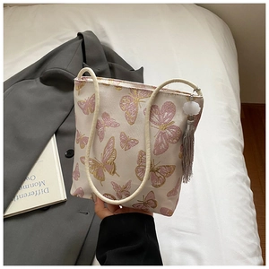 Close-up of elegant butterfly embroidery and tassel on a beige canvas tote bag