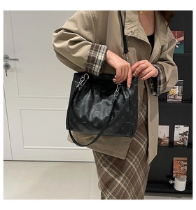 Close-up of black tote bag featuring repeating cartoon bear prints and metal chain strap