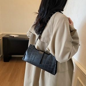 Elegant black crocodile pattern underarm bag with woven chain strap shown on a model