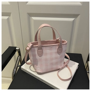 Detail of pink gingham bucket bag with adjustable strap and golden hardware accents