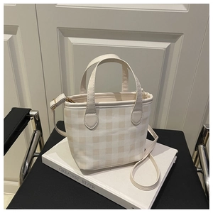 Close-up of a plaid tote bag with beige and yellow checks on a minimalist indoor setting