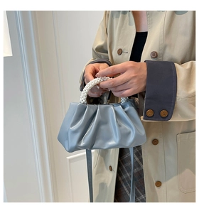 Detail of sky blue pleated cloud bag with white pearl handle and thin leather strap
