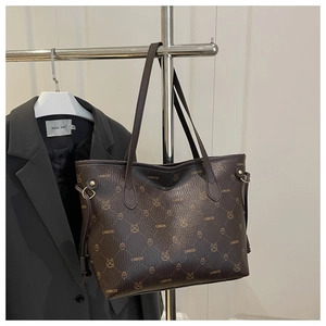 Close-up of deep brown tote bag featuring luxury monogram print and pebbled leather texture