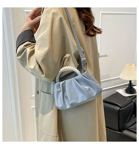 Detailed view of the pleated light blue handbag with elegant pearl bead handle and strap