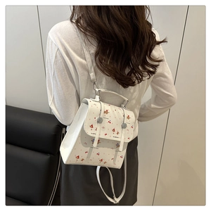 Petit sac à dos blanc à imprimé cerises porté par un mannequin dans un salon