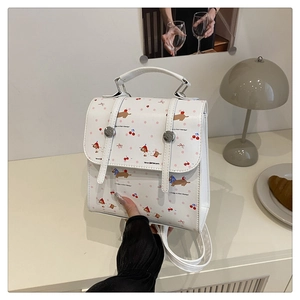 Vue détaillée d'un mini sac à dos en cuir blanc avec motifs de teckel et cerise