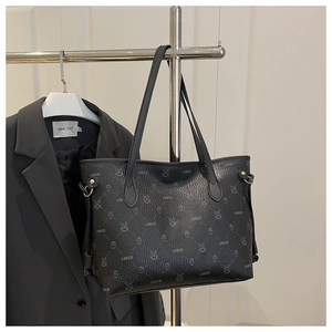 Close-up of black tote bag with rabbit print and litchi grain texture on metal stand