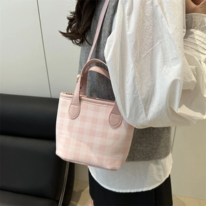 Pink plaid canvas bucket bag with dual handles and shoulder strap shown on model