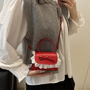 Mini red leather handbag with bow detail and white lace trim shown on a model