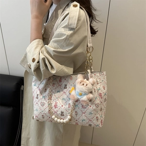 Sac fourre-tout à fleurs avec chaîne perlée et pendentif ours porté par un mannequin