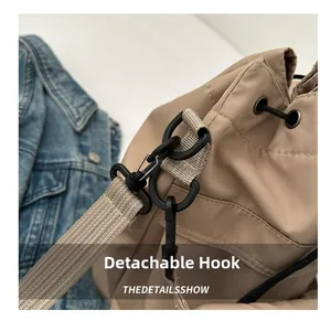 Detailopname van de kaki nylon tas met zwarte afneembare draaihaak en geweven textuur
