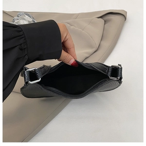 Detail view of the black lychee pattern leather dumpling bag with silver metal zipper