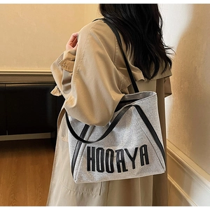 Detail of the minimalist fabric tote bag with black leather straps and HOORAYA logo print