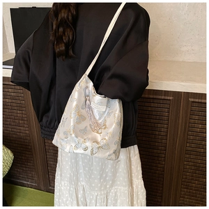 Detailed shot of striped bucket bag with silk butterfly pattern and elegant fringe tassel