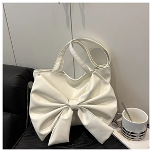 Detail of white tote bag featuring large bow design and soft PU leather material