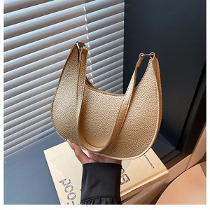 Detailed view of pale gold crescent bag with litchi grain texture and metal zipper