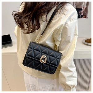 Détail du sac bandoulière noir matelassé avec boucle en U dorée et bandoulière chaîne