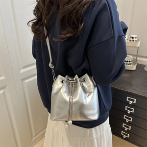Silver metallic drawstring bucket bag with chain strap and pearl accents for women