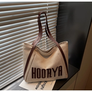 Detailed view of canvas tote bag featuring brown HOORYA lettering and leather straps