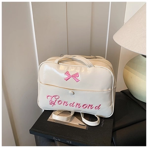 Detail of cream white PU leather tote bag with pink bow embroidery and front buckle pocket