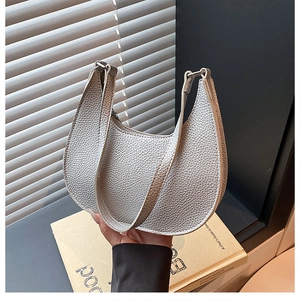 Detail of silver lychee texture on crescent hobo bag held against a sunlit background
