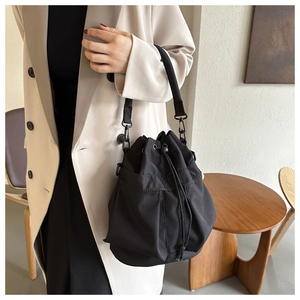 Detail of black drawstring bucket bag showing durable nylon fabric and metal hooks