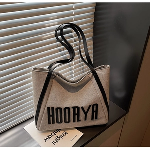 Detail of canvas tote bag showing black leather strap and bold HOORYA text print