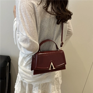 Vintage wine red leather crossbody bag with gold V-buckle and structured top handle design