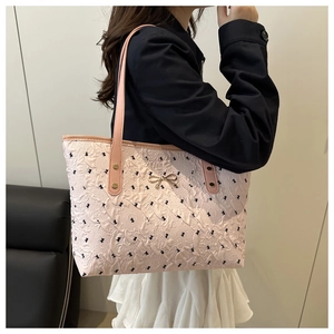 Détail d'un sac cabas rose plissé avec imprimés nœuds noirs et ornement doré chic