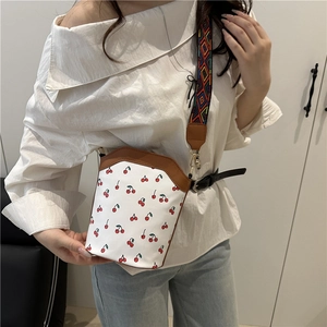 Minimalistische weiße Eimertasche mit Kirschdruck und buntem Jacquard-Gurt am Modell