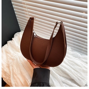 Detail of brown lychee leather texture on a crescent shoulder bag with silver zipper