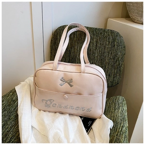 Detail of pink glossy leather tote featuring an embroidered silver bow and brand logo