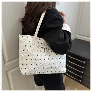 Détail du sac cabas en jacquard blanc avec motifs nœuds noirs et boucles dorées