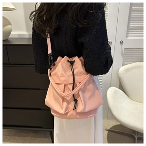 Detailweergave van een roze nylon bucketbag met trekkoordsluiting en geplooide details