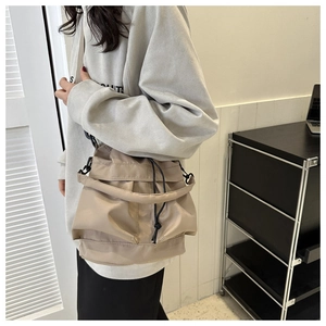 Détail d'un sac seau en nylon kaki avec cordon de serrage et plis sur la bandoulière