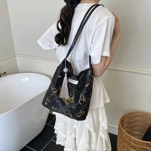 Women's black shoulder bag with gold butterfly embroidery and purple tassel charm
