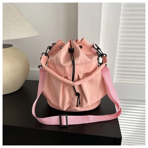Pink drawstring bucket bag detail with black toggle and adjustable textile shoulder strap