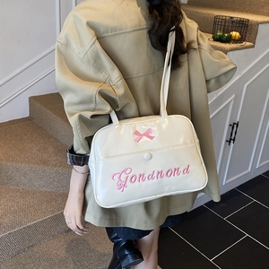 Chic white high-gloss tote bag with pink bow embroidery shown on a model's shoulder