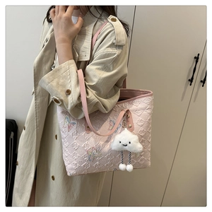 Pink tote bag detail with quilted M pattern and colorful butterfly embroidery on display