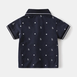 Detail view of boys' navy polo shirt featuring white star and sailboat prints
