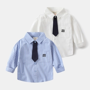 Dettaglio di camicie da bambino bianche e a righe blu con cravatte e ricami eleganti