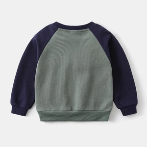 Macro detail of breathable waffle knit fabric and ribbed cuffs on raglan sleeve sweatshirt