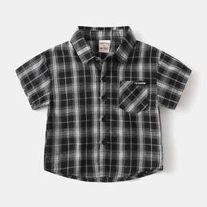Detail of boys' checkered short-sleeve shirt showing cotton fabric and fashion label