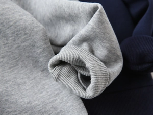 Detail of ribbed cuffs and soft fleece lining on grey and navy cotton blend hoodies