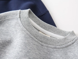 Detailed close-up of ribbed crewneck and stitching on gray and navy cotton sweatshirts