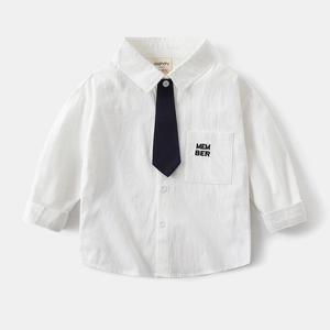 Dettaglio camicia bianca in cotone per bambini con cravatta blu e taschino sul petto